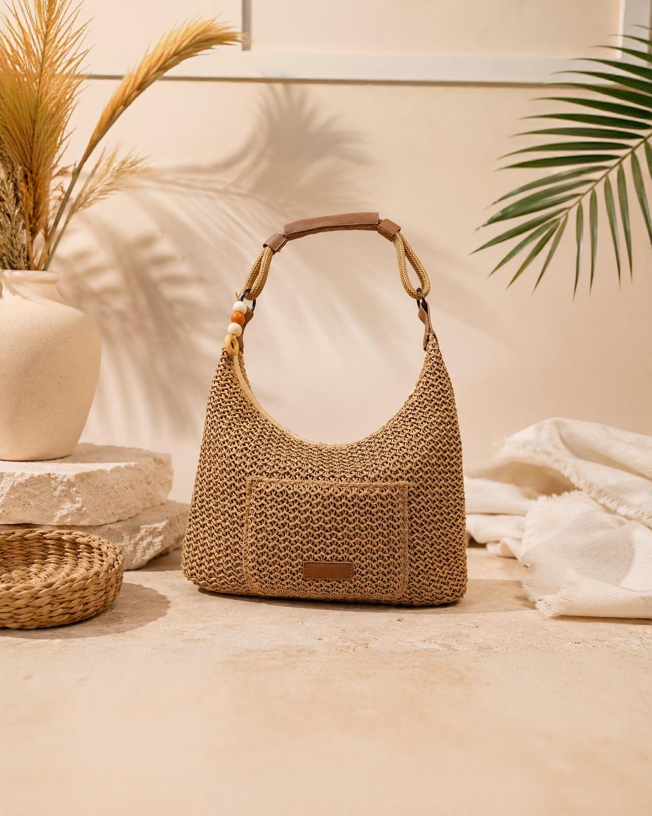 Bolso Hobo Tramuntana de EUTEA, un bolso de hombro con diseño de media luna en tejido texturizado marrón paja, con asa reforzada en piel marrón y detalle de cuentas decorativas.