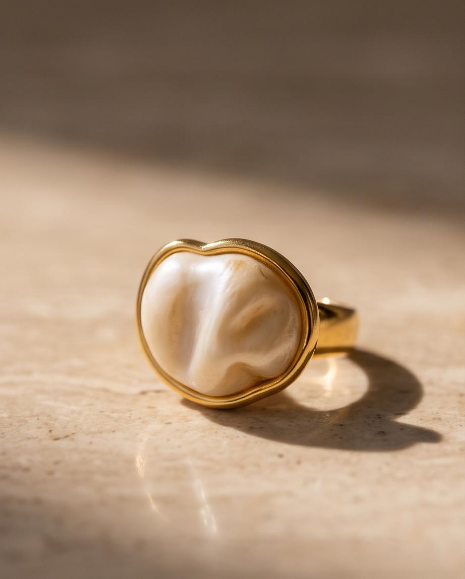 Anillo Calpe dorado con piedra efecto perla y diseño ajustable.
