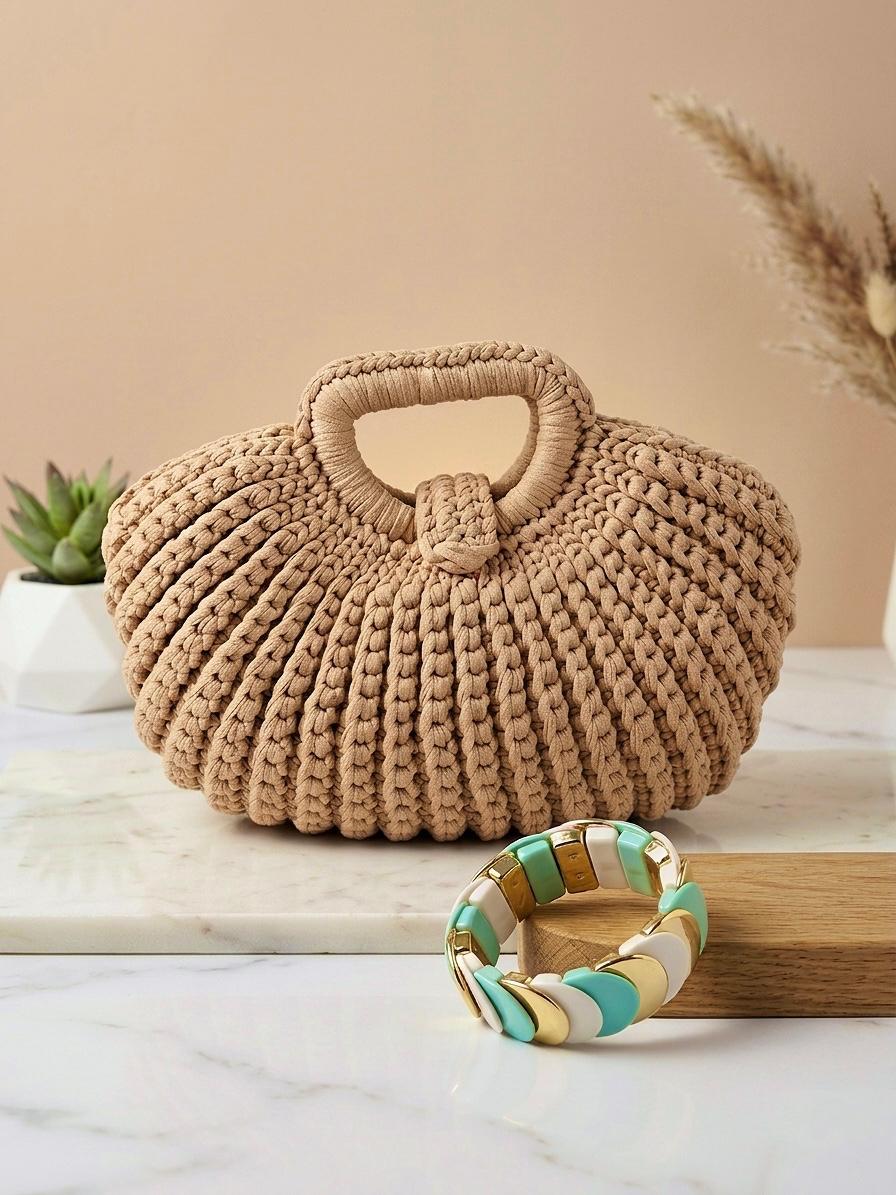 Bolso de mano de la marca EUTEA modelo Arenys, confeccionado en punto trenzado grueso de color beige taupe con diseño acanalado vertical, asa superior integrada y cierre de imán, fotografiado en un set minimalista junto a una pulsera esmaltada.