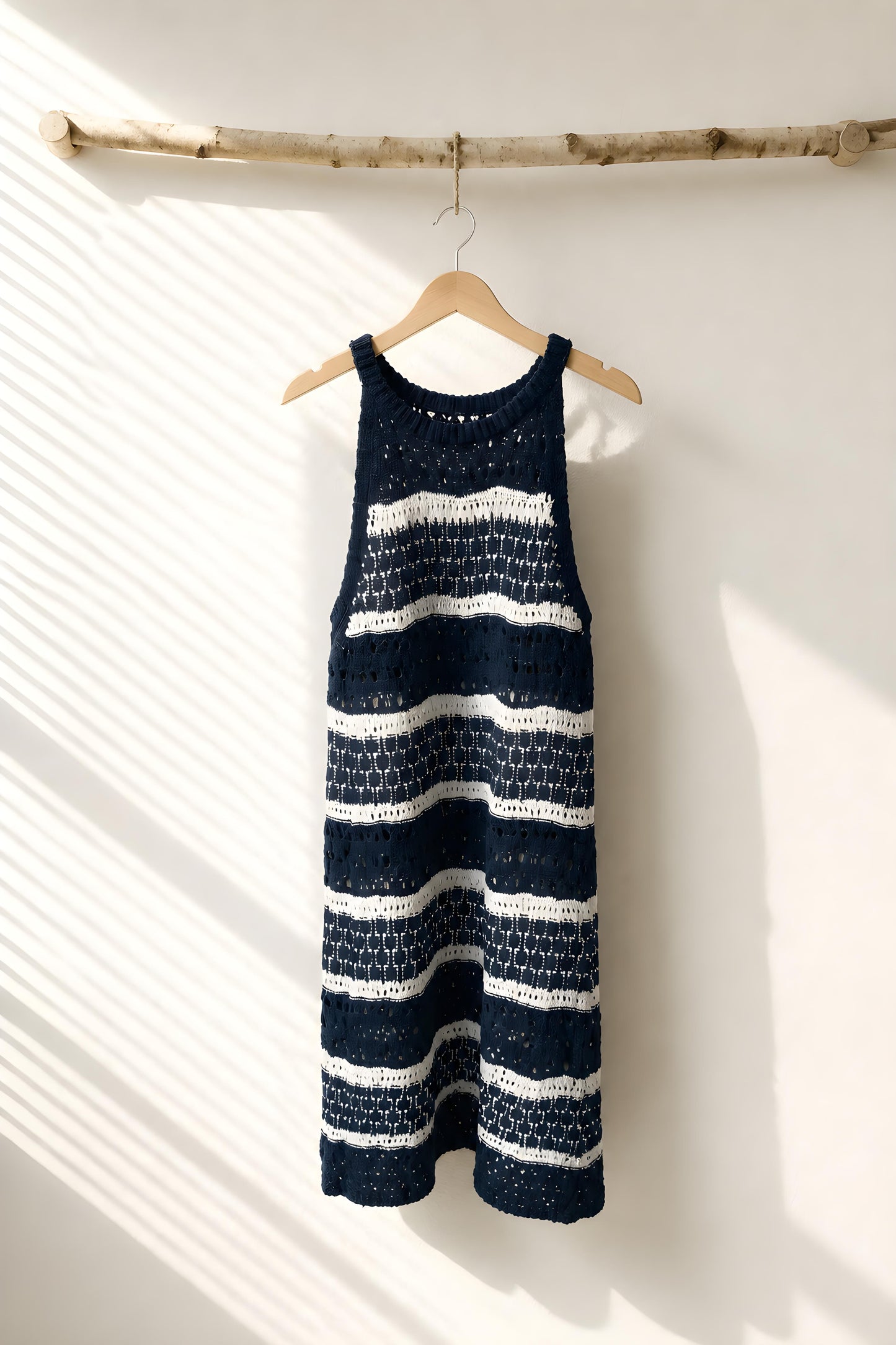 Vestido corto de crochet a rayas color blanco y azul colgado en percha de madera - Eutea Beachwear
