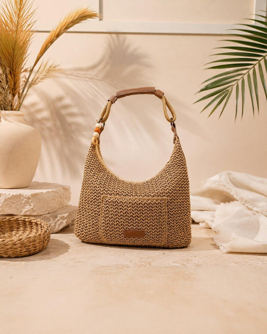 Bolso Hobo Tramuntana de EUTEA, un bolso de hombro con diseño de media luna en tejido texturizado marrón paja, con asa reforzada en piel marrón y detalle de cuentas decorativas.