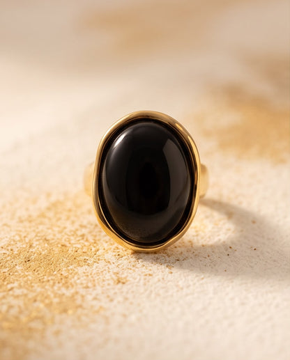 Anillo Cadaqués dorado con piedra negra y diseño ajustable.