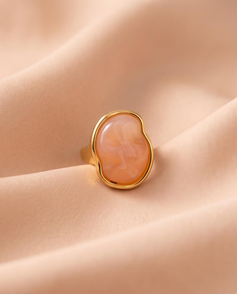 Anillo Calpe dorado con piedra coral de efecto natural.