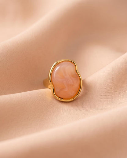 Anillo Calpe dorado con piedra coral de efecto natural.