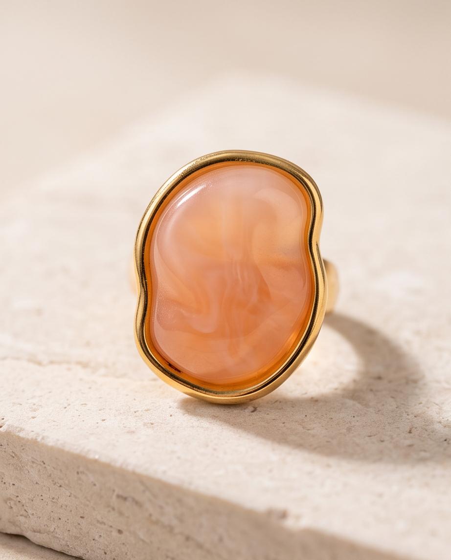 Anillo Calpe dorado con piedra coral de efecto natural.