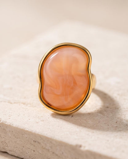Anillo Calpe dorado con piedra coral de efecto natural.