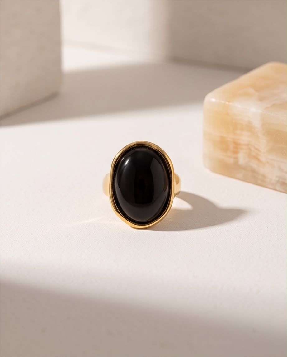 Anillo Calpe dorado con piedra negra y diseño ajustable.