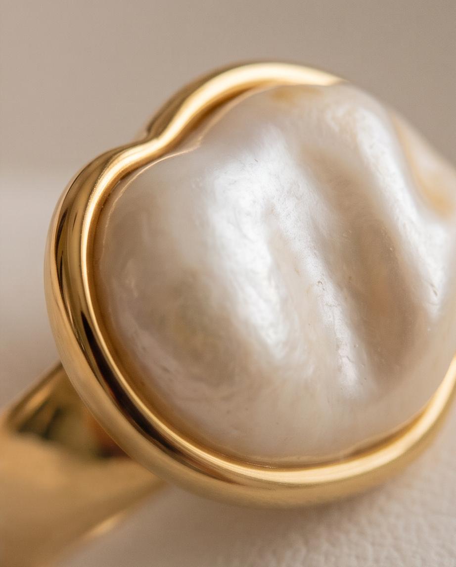 Anillo Calpe dorado con piedra efecto perla y diseño ajustable.
