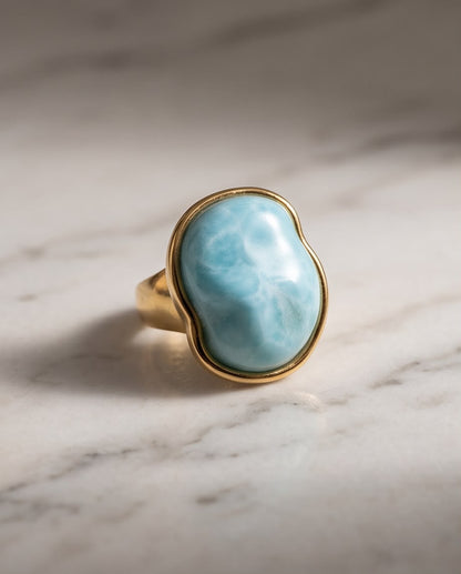 Anillo Calpe dorado con piedra turquesa de acabado natural.
