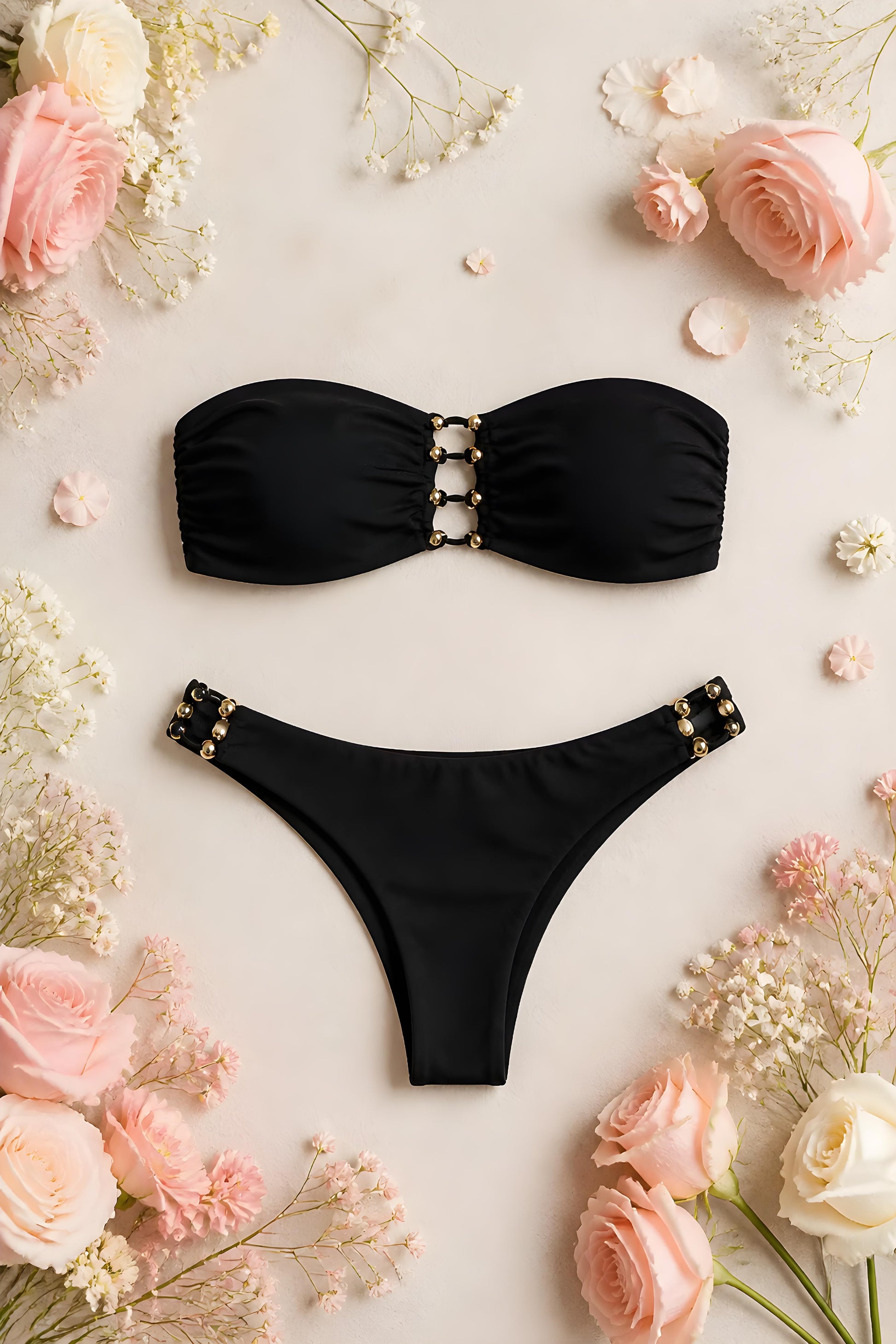Fotografía de producto en plano zenital del bikini bandeau Amalfi negro rodeado de rosas, Eutea.