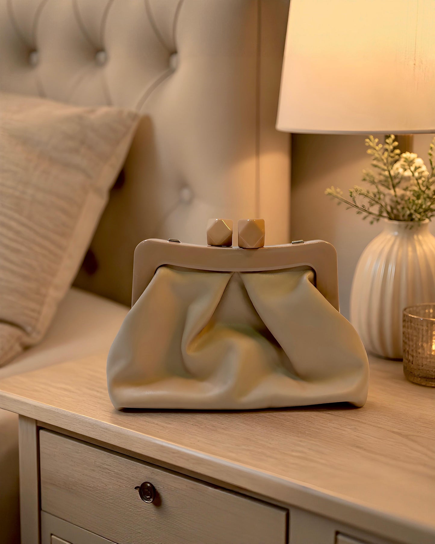 Bolso de mano tipo pouch Sutton de EUTEA, confeccionado en piel sintética suave color camel con un elegante diseño fruncido y boquilla rígida superior de acrílico brillante con cierre de imán.