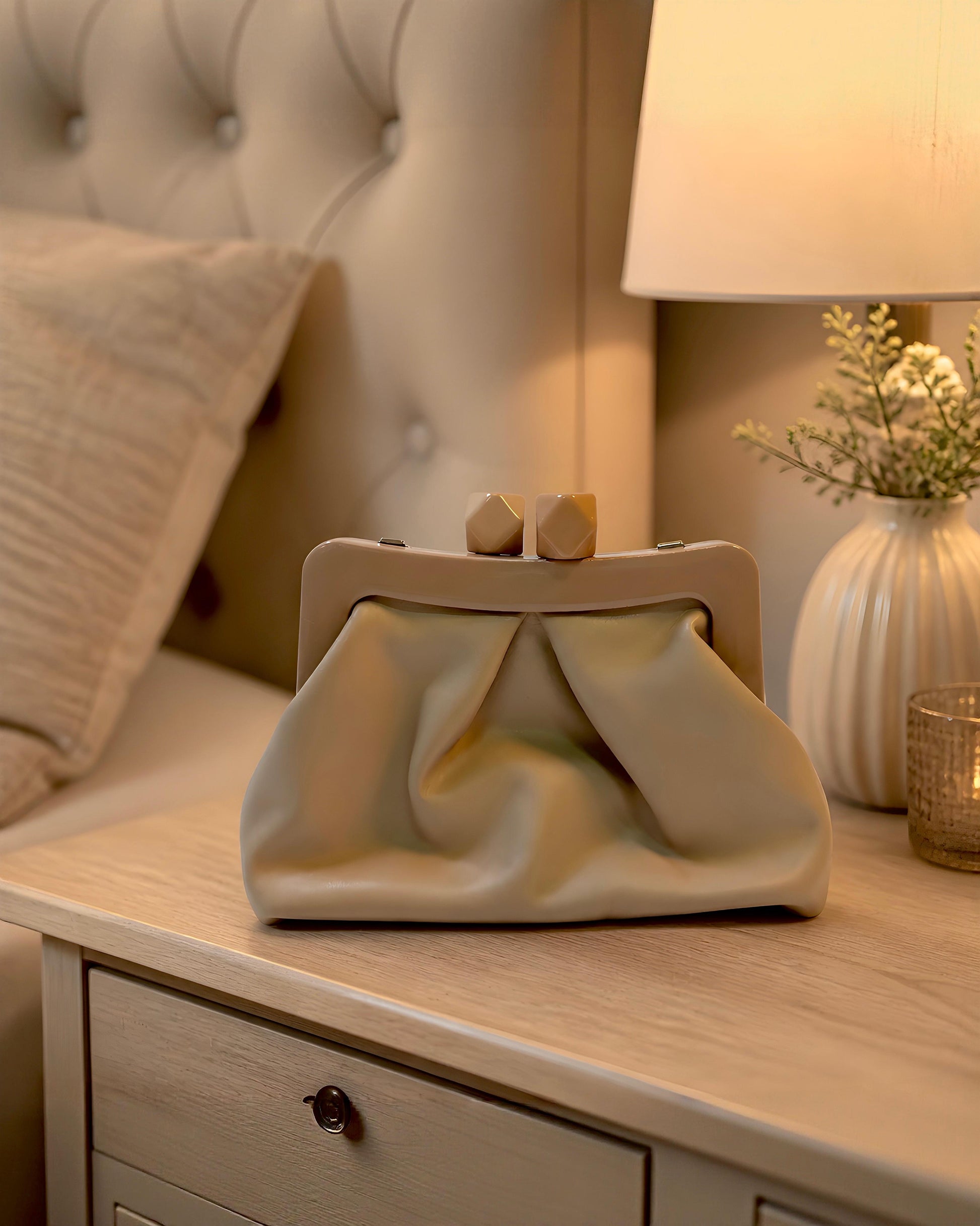 Bolso de mano tipo pouch Sutton de EUTEA, confeccionado en piel sintética suave color camel con un elegante diseño fruncido y boquilla rígida superior de acrílico brillante con cierre de imán.