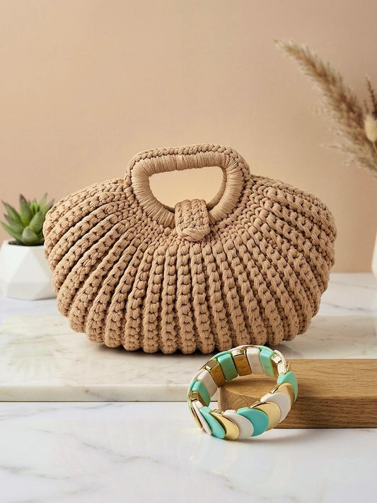 Bolso de mano de la marca EUTEA modelo Arenys, confeccionado en punto trenzado grueso de color beige taupe con diseño acanalado vertical, asa superior integrada y cierre de imán, fotografiado en un set minimalista junto a una pulsera esmaltada.