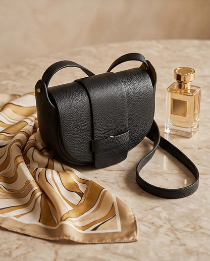 Bolso bandolera Malvarrosa en piel italiana negra con cierre magnético sobre mesa de mármol.