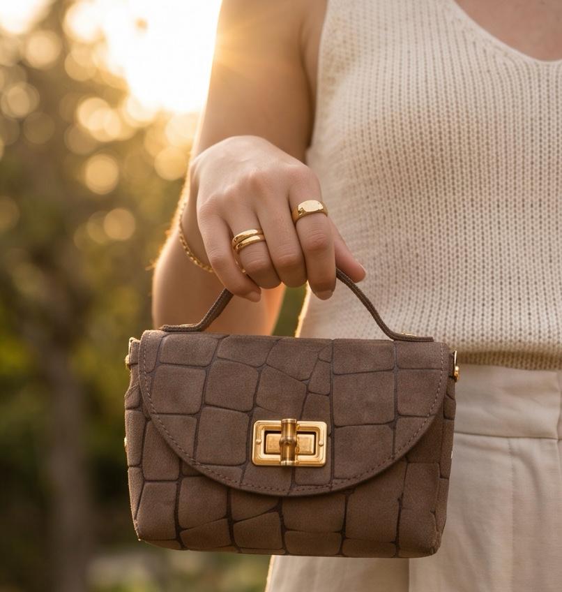 Bolso mini Trancoso de piel marrón llevado por el asa superior