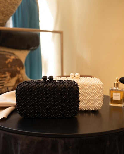 Detalle de clutch de fiesta con abalorios efecto perla en negro y marfil