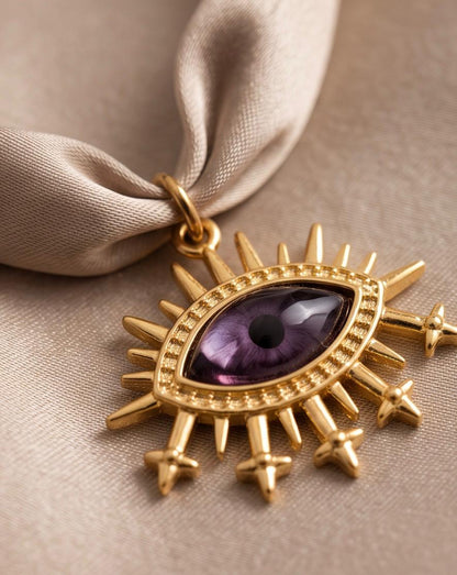 Detalle del colgante dorado en forma de ojo violeta del Collar Amuleto.