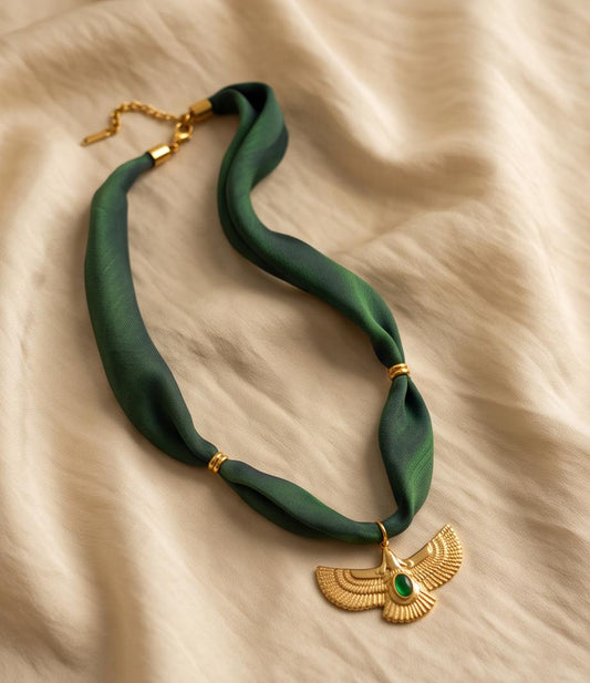 Collar Císter de color verde esmeralda con colgante dorado sobre fondo elegante.