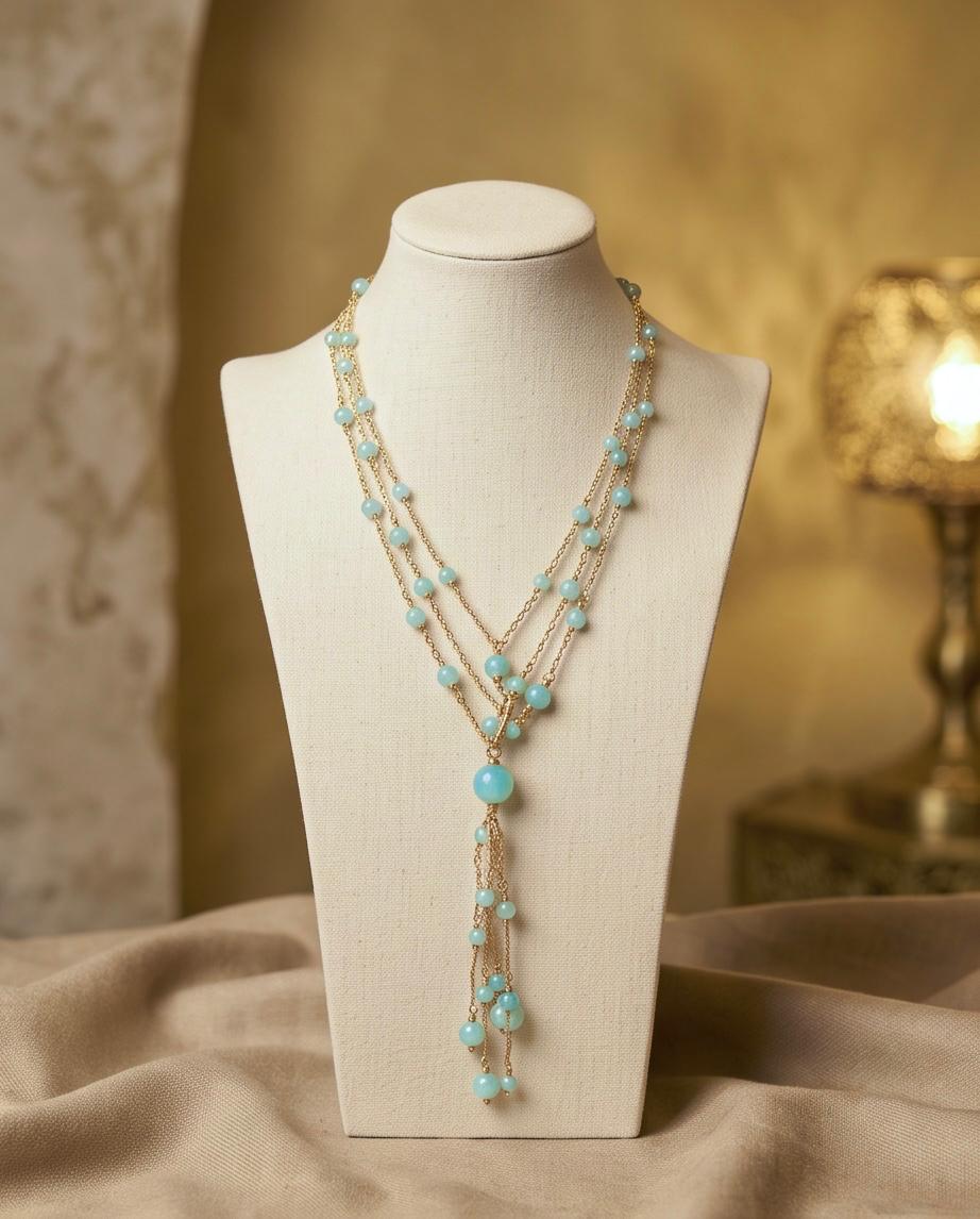 Collar largo de cadenas doradas con cuentas azul turquesa y detalle en cascada.