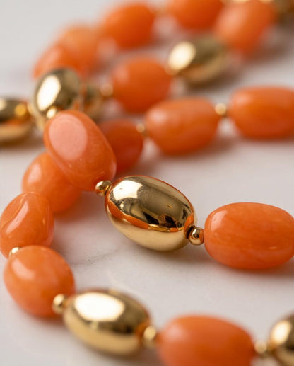 Detalle de las cuentas naranjas y piezas metálicas doradas del collar Amara.