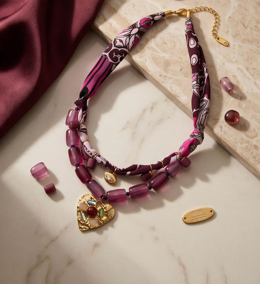 Collar Pals de 55 cm con tejido satinado, cuentas decorativas y colgante corazón sobre fondo de mármol.