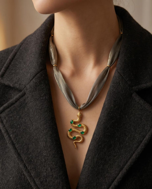 Collar Serpiente Esmeralda de tejido gris y acero dorado llevado al cuello.