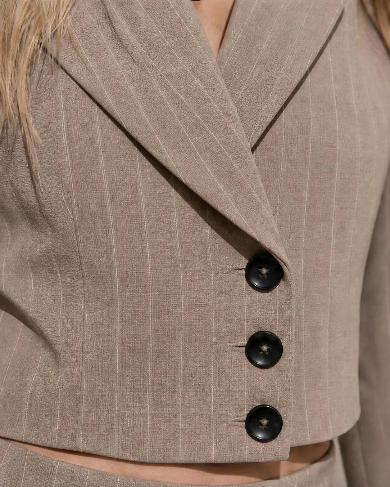 Primer plano de la blazer corta del conjunto Fabra beige de EUTEA, destacando el cuello de solapa y el cierre de tres botones negros