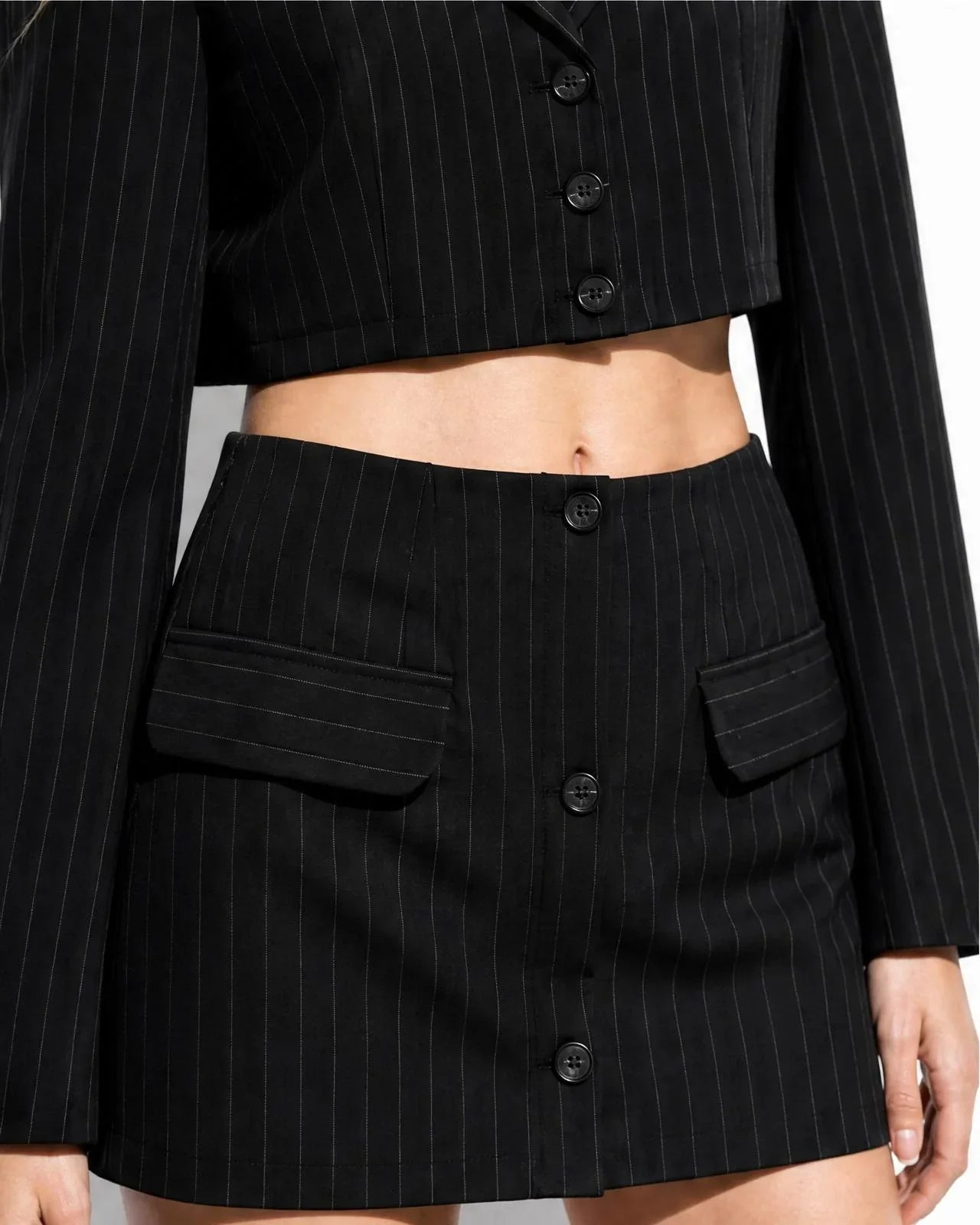 Conjunto de dos piezas de sastre Fabra en color negro con sutil raya diplomática de la marca EUTEA, mostrando la blazer corta y la falda-pantalón de frente con efecto minifalda