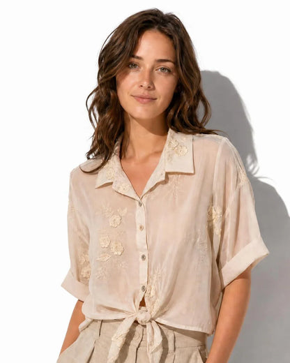 Blusa translúcida beige Vilassar con bordados florales y nudo en la cintura de la marca EUTEA.