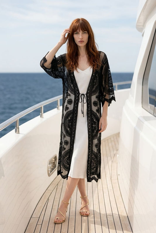 Vista frontal de la modelo con el kimono de encaje negro Segovia de Eutea atado a la cintura sobre un vestido lencero blanco.