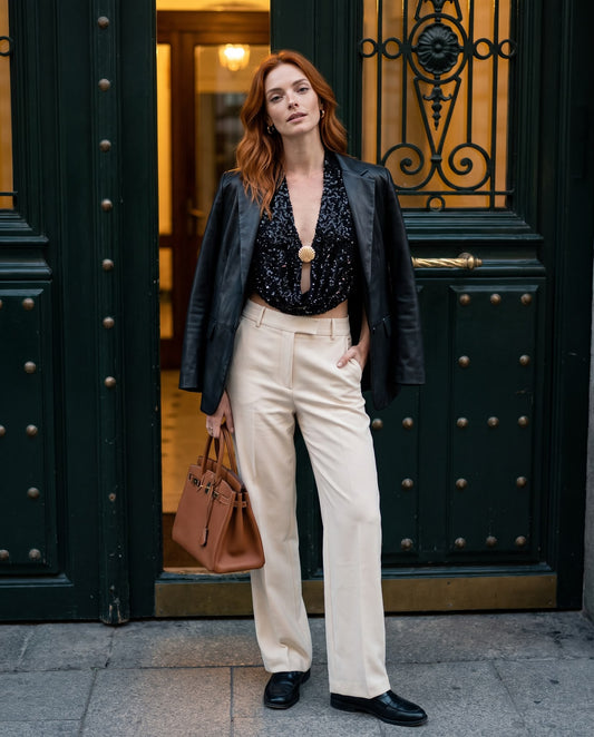 Look de noche con el top de lentejuelas Aragon, blazer negra sobre los hombros y pantalón beige.
