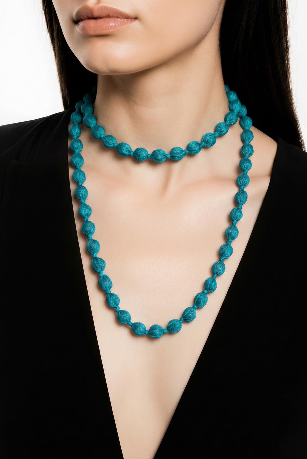Modelo luciendo con doble vuelta el collar textil Begur en color azul turquesa de EuTea, confeccionado en paño y madera.