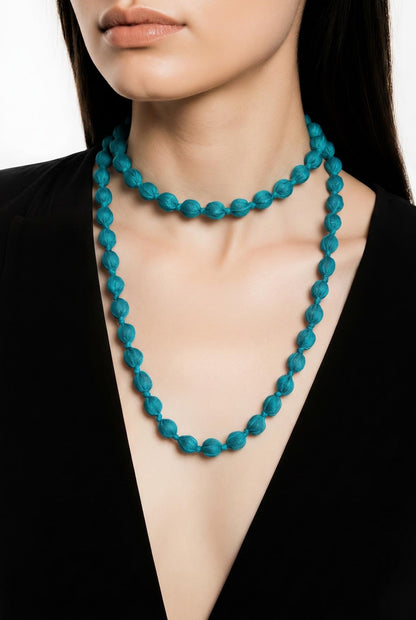 Modelo luciendo con doble vuelta el collar textil Begur en color azul turquesa de EuTea, confeccionado en paño y madera.
