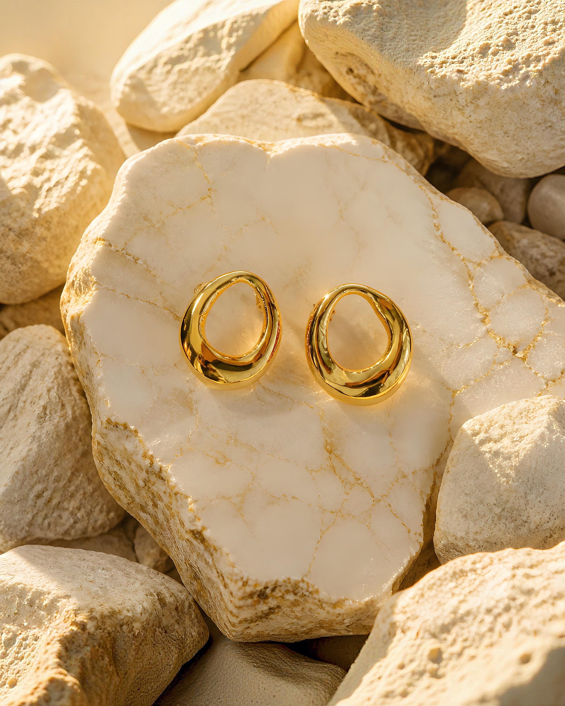 Par de pendientes dorados Tarragona de EuTea en acero inoxidable, con diseño de gota orgánica redondeada expuestos sobre piedra natural.