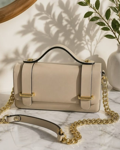 Vista cenital del bolso de mano de cuero rígido modelo Cunit de la marca EUTEA en color camel, mostrando el diseño plano de su asa superior y los acabados metálicos dorados en una mesa iluminada por el sol.