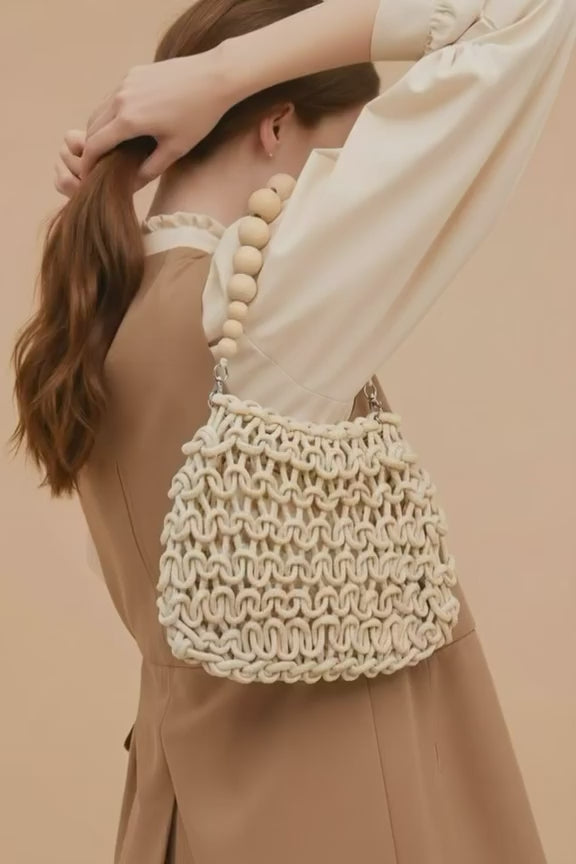 Vista detallada del bolso Calella de EUTEA, mostrando el intrincado tejido de nudos de macramé, el cierre superior de cremallera y el forro interior estructurado en tono beige.