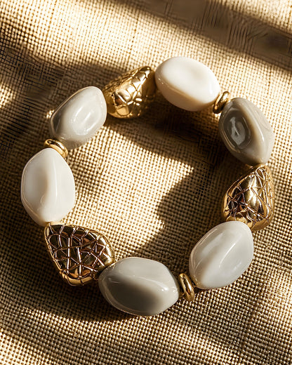 Pulsera elástica Puigcerda de EuTea con cuentas de resina orgánica en color gris y blanco brillante, combinadas con eslabones dorados texturizados.