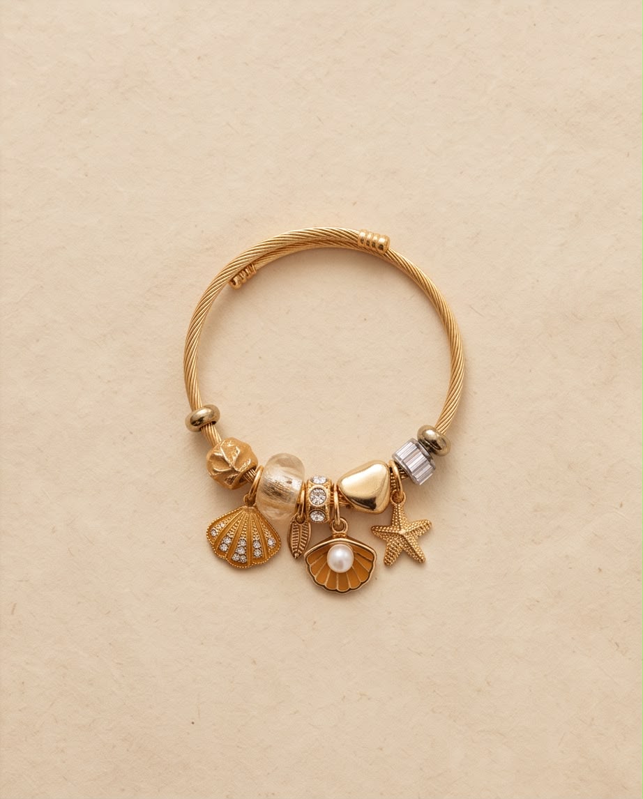 Pulsera Mojácar dorada con charms inspirados en el mar sobre fondo claro.