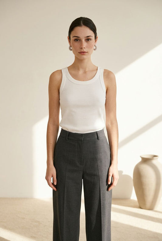 Modelo de frente vistiendo el top básico de canalé premium blanco Vizcaya de Eutea, combinado con pantalón de vestir gris.