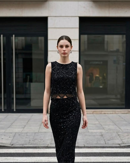 Modelo vistiendo el Top Corto de Pedrería Marconi en color negro de Eutea, combinado con falda midi de lentejuelas en un paso de peatones.